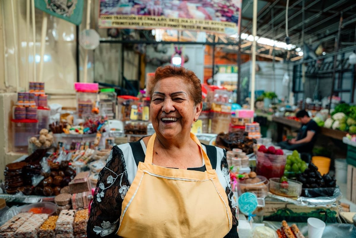 Feirante sorrindo atrás da banca do próprio negócio