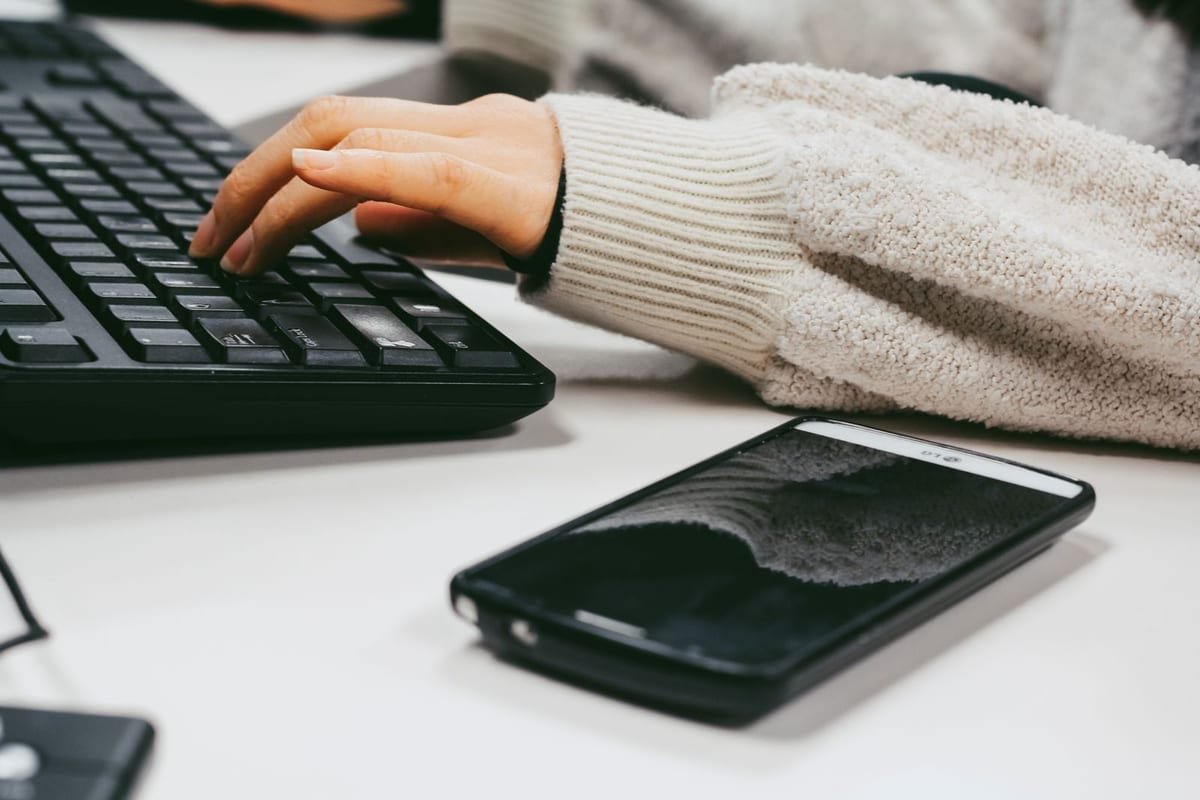 Celular ao lado do teclado, com uma conversa aberta